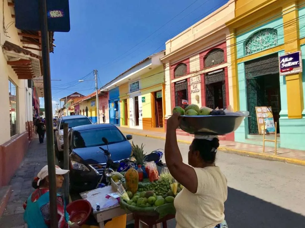 Local woman is caring a fruit basket on top of her head in Leon, Nicaragua