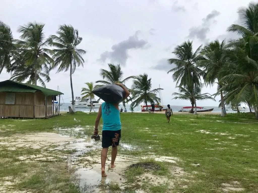 Nace is carrying his backpack wrapped with a plastic bag to protect from the rain while leaving the Guna Yala people from Panama
