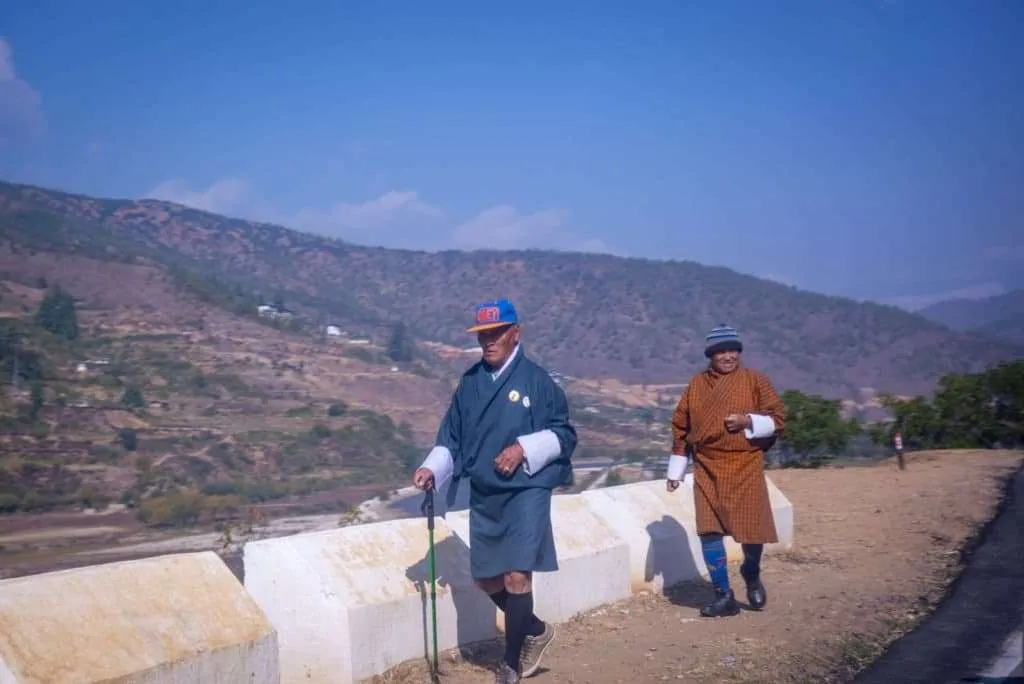 Bhutan - people, country, culture, men in gho walking along the road