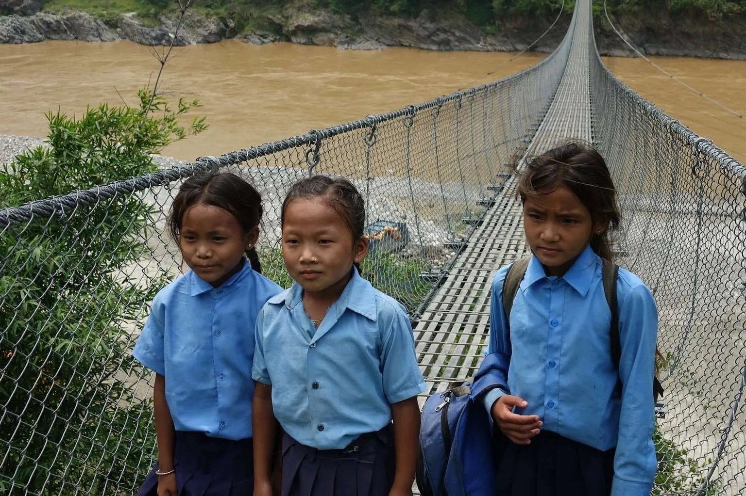 Nepal itinerary, meeting Nepali people - schoolgirl on a suspension bridge