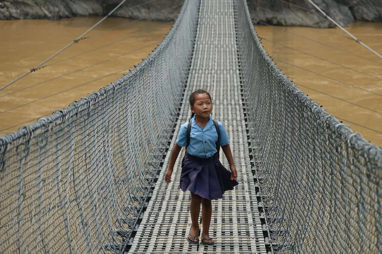 Nepal itinerary, meeting Nepali people - schoolgirl on a suspension bridge